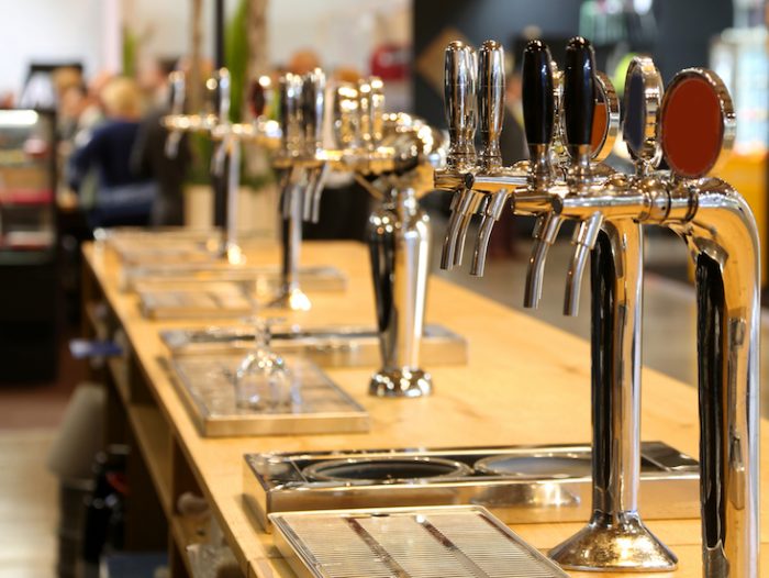 many draft beer taps lined up on the counter of a pub